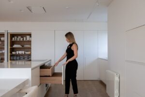 Homeowner sits at a bright, modern kitchen island, thoughtfully reviewing papers, representing the strategic decision-maki...